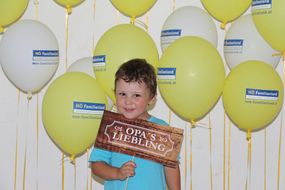 Ein Bub hält bei den NÖ KinderSommerSpielen 2016 ein Schild mit "Opa's Liebling" in die Kamera.