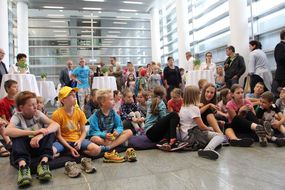 Kinder sitzen beim Ferienauftaktfest 2016 und hören gespannt zu.