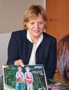 Landesrätin Schwarz lächelt und zeigt ein Magazin her.