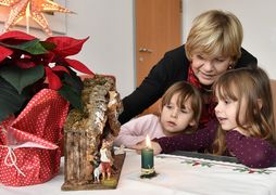 Landesrätin Schwarz begutachtet mit zwei Mädchen eine kleine Krippe.