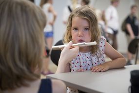 Kleines Mädchen versucht, mit der Querflöte zu musizieren