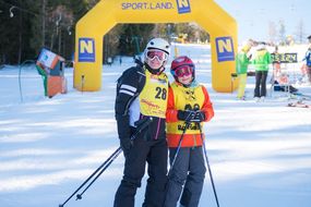Frau und Kind mit Skihelm lächeln bei den Familienskitagen 2017 in die Kamera.