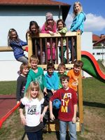 Kinder der schulischen Nachmittagsbetreuung haben sich um die Rutsche für ein Gruppenbild zusammengestellt.